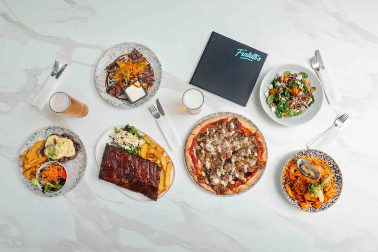 Plates of pizza and shared dishes on a table at Fratelli's